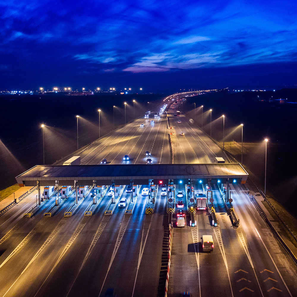 Image of car and trucks entering toll booths at nigh