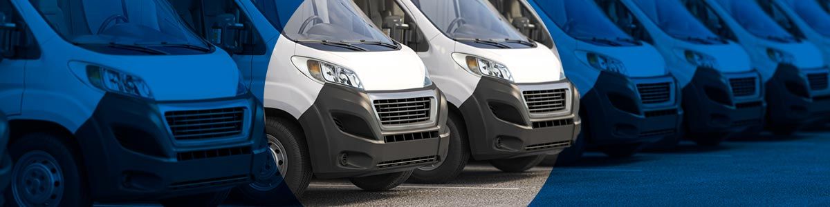 A row of white delivery trucks are parked in a line 