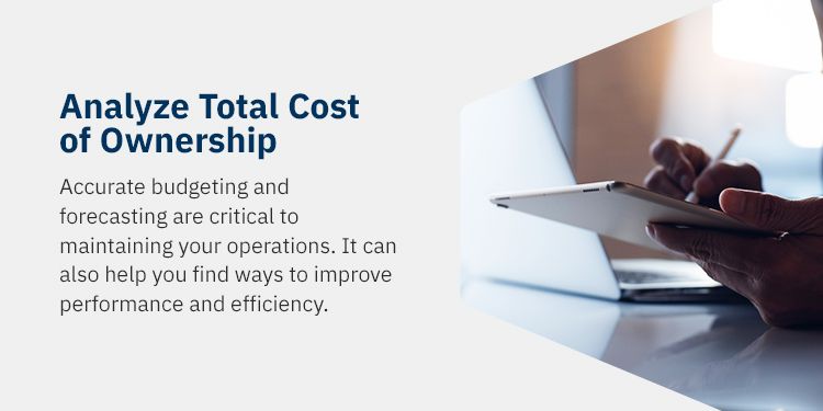 On a cream background, blue text reads "Analyze Total Cost of Ownership - accurate budgeting and forecasting are critical to maintaining your operations. It can also help you find ways to improve performance and efficiency" To the right of the text is an image of a set of hands, writing on a tablet beside an opened laptop