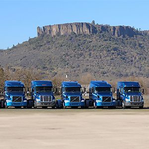 combined transport fleet of trucks in front of mountain