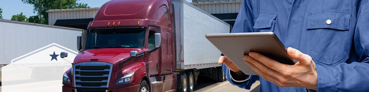 A man wearing a blue shirt is holding an ipad as he stands in front of a red truck attached to a white trailer